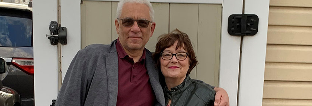 A smiling middle-aged couple standing in front of a barn.