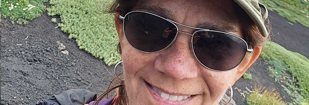 A close-up photo of a women waring a hat and sunglasses