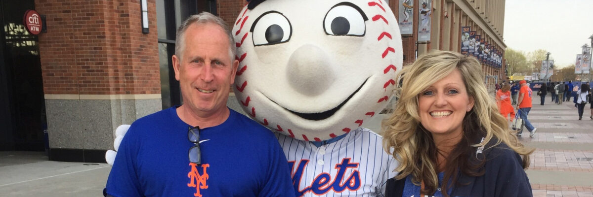 NYPC patient, Debi Walsh Lembo, happily posing with her husband next to the Mr. Mets mascot.