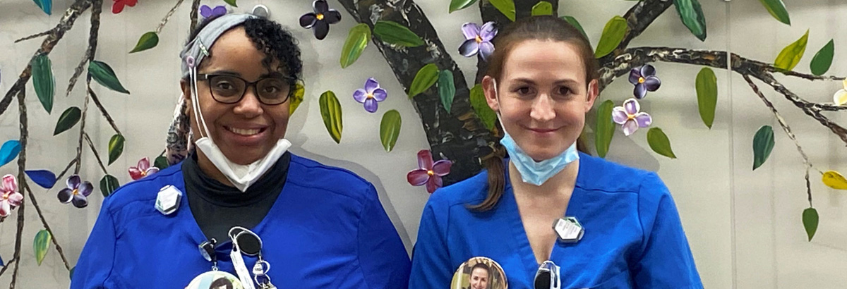 Two female nurses standing against a colorful wall