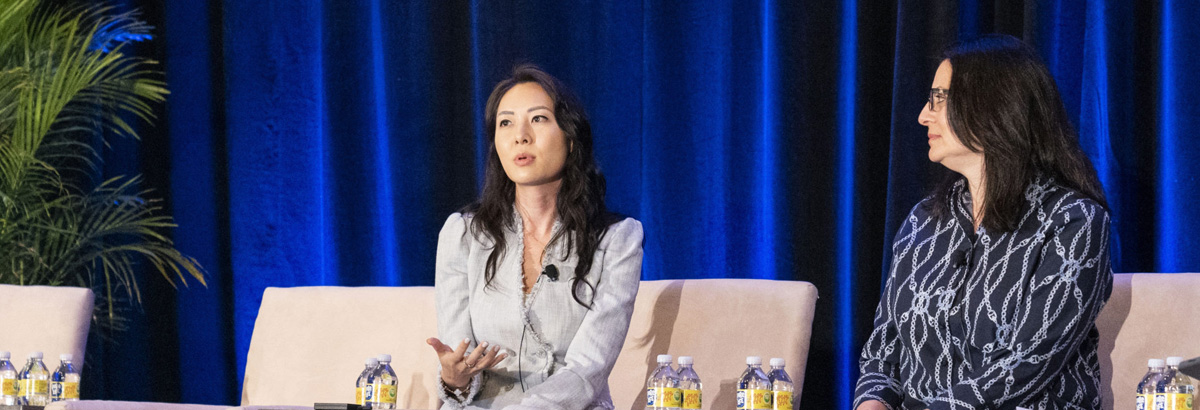 Two women seated on stage and presenting at conference