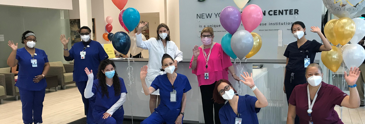 A group of nurses waving and holding balloons