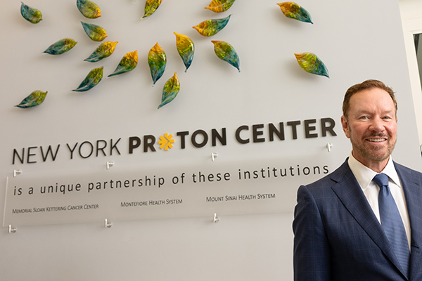 Christopher Panczner, CEO of the New York Proton Center stands in front of the center's lobby signage.