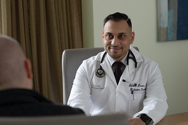 Dr. Shaakir Hasan of the New York Proton Center having a consultation with a patient in an office setting.