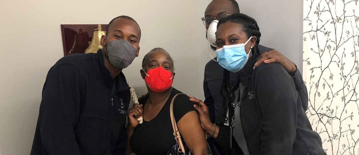 A woman surrounded by three radiation therapists